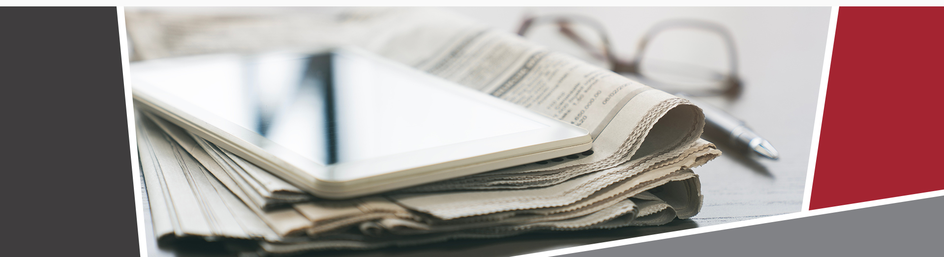 An image of a newspaper with an iPad on top, with a pen and glasses on the right of the paper. 