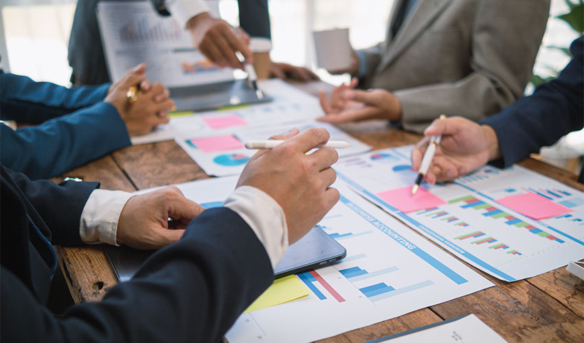 Group of people discussing different charts and information in a committee meeting
