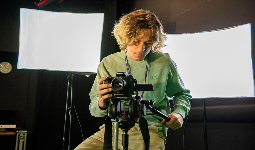 An image of a student holding a camera looking at the camera's screen.