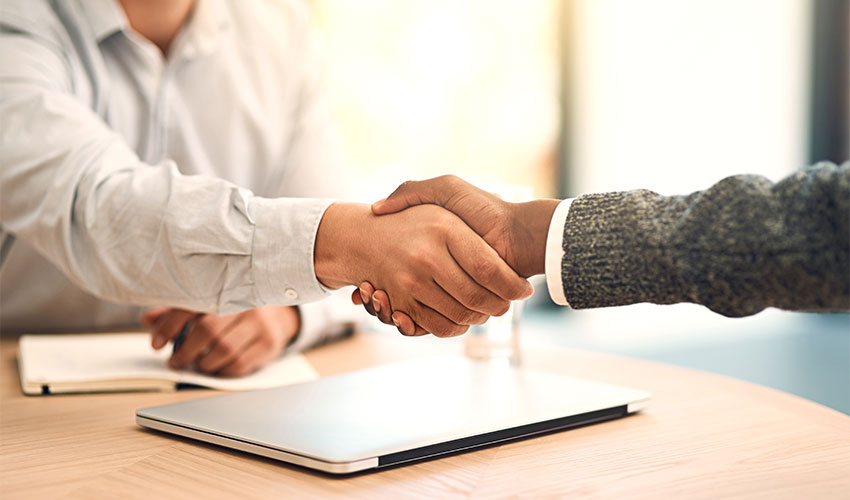 Two people handshaking over a contract