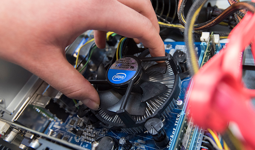 An image of a student building a pc, holding a component into place.