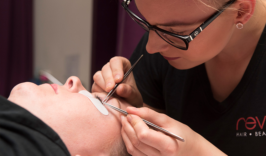 An image of a beauty student treating a patient's eyelashes.