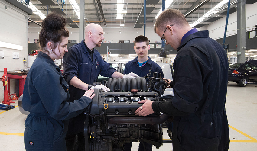 An image of students and staff around an engine.