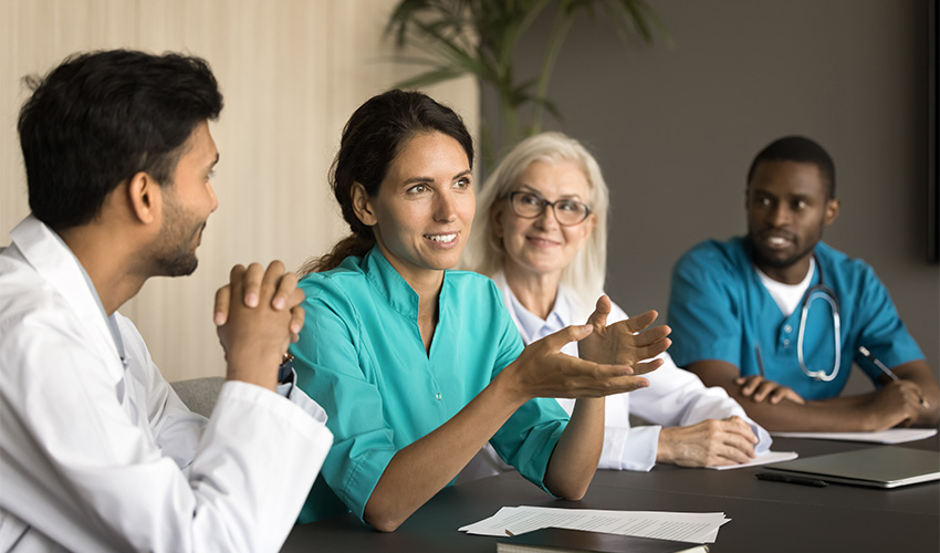 A group of four doctors sat at a table, discussing with each other. 