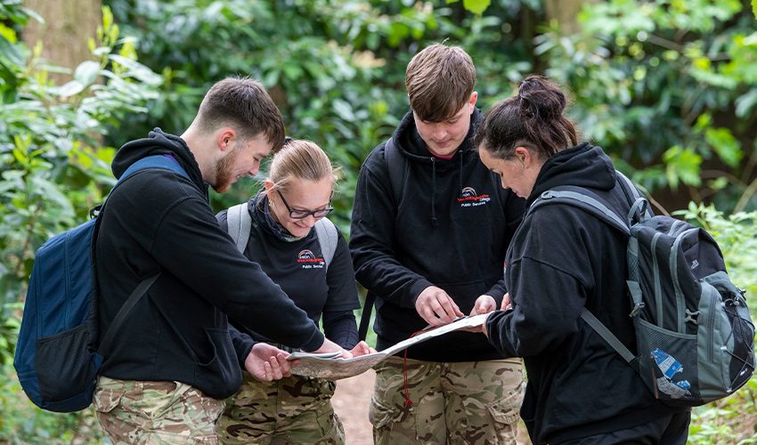 An image of students gathered around a map pointing and smiling.