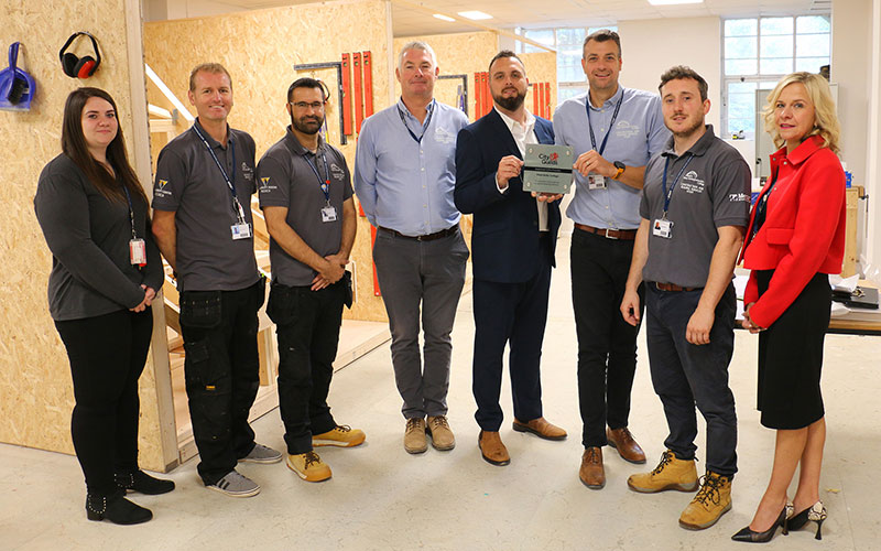City & Guild's Johnathan Price (4th right) presents apprenticeship manager Paul Stringer with the plaque