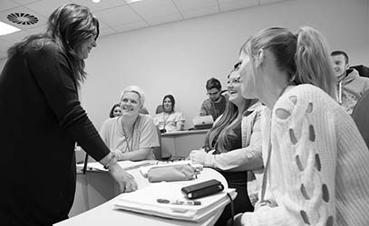 Adult learners in a classroom with a teacher stood in the front.