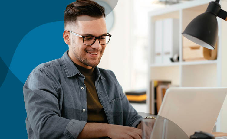 Photo of a young male adult sat looking at a laptop screen.