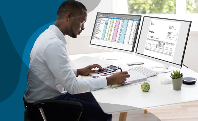 Image of a male adult sat infront of two monitors displaying financial data.