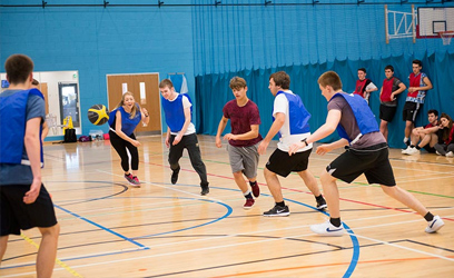 Image of a group of people playing basketball indoors.