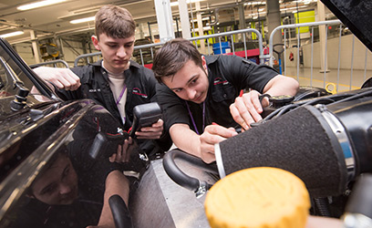 Image of twon young men working on a car engine.