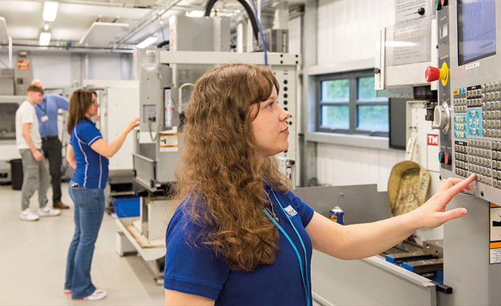 Image of a young women looking at a control panel for an engineering piece of equipment.