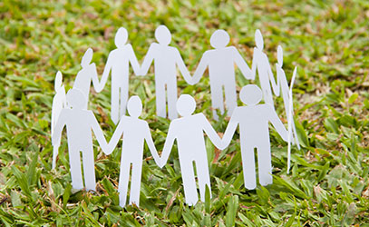 photo of paper people holding hands in a circle on the grass