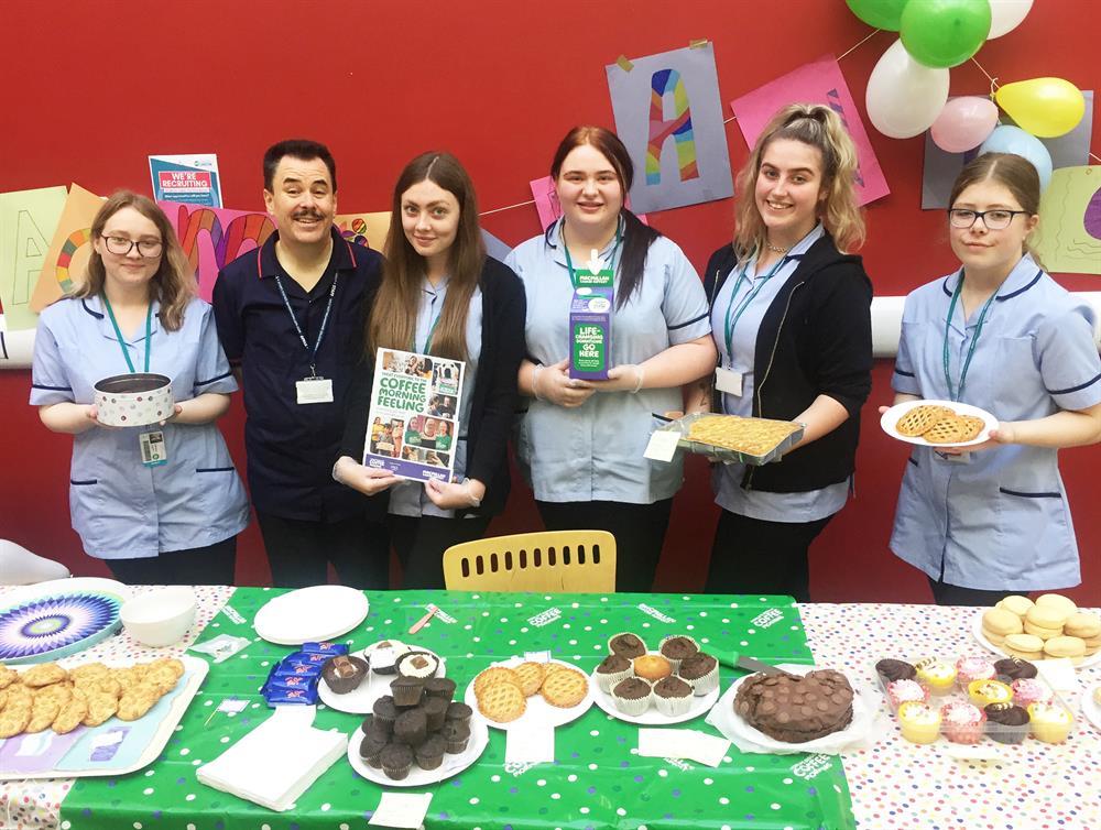 Proud tutor Martin Cook (2nd left) with health and social care students and their tasty fayre