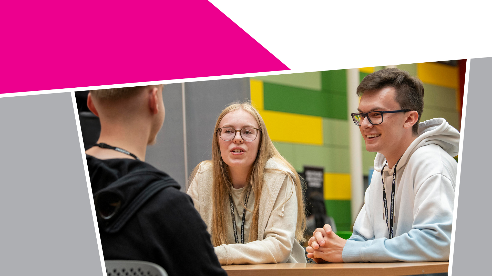 A group of students sat at a table smiling at each other mid-conversation.