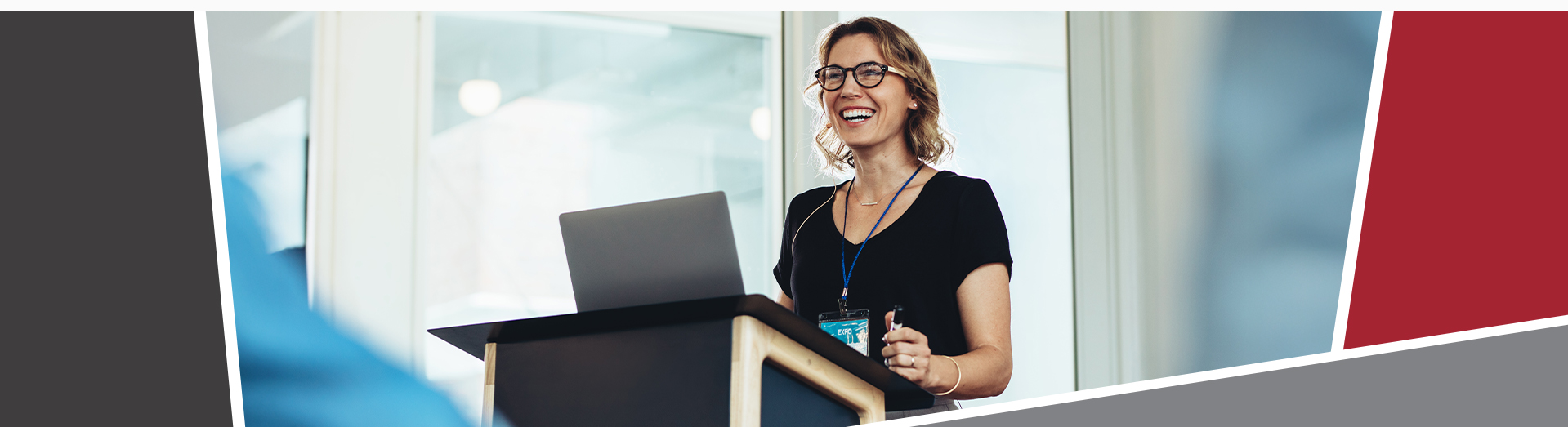 A smiling woman standing behind a podium with a laptop, giving a talk.