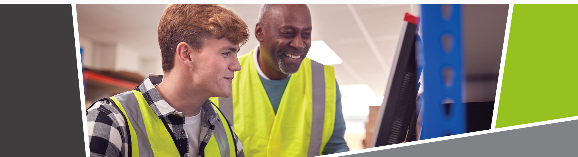 An image of an apprentice and a mentor smiling looking at a computer screen, wearing hi-vis jackets.